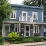 Blue clapboard house with a front porch and garden in Vieux-Sainte-Rose, Laval